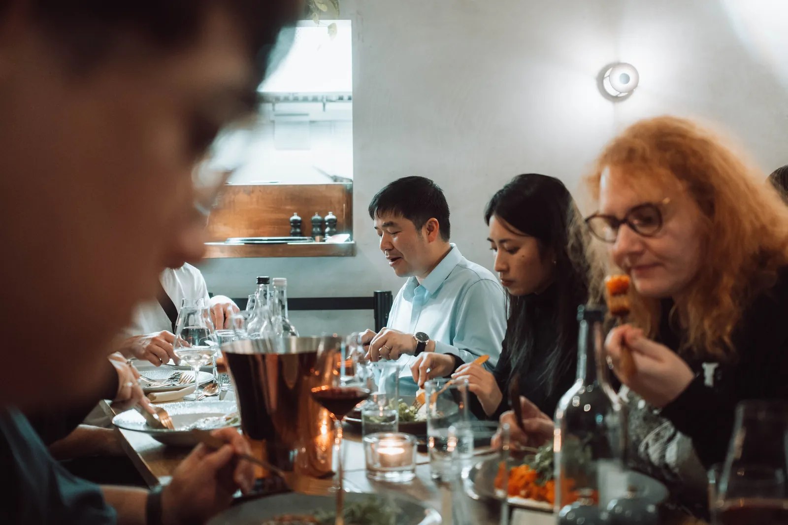 A group of friends sharing plates of food around a restaurant table