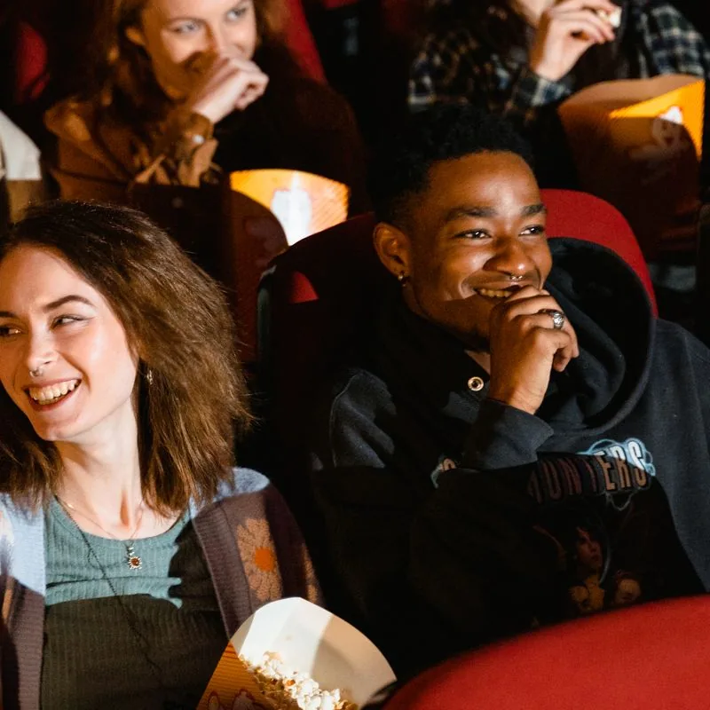 Friends laughing over popcorn at the movies